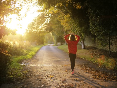 young person walking along road in sun