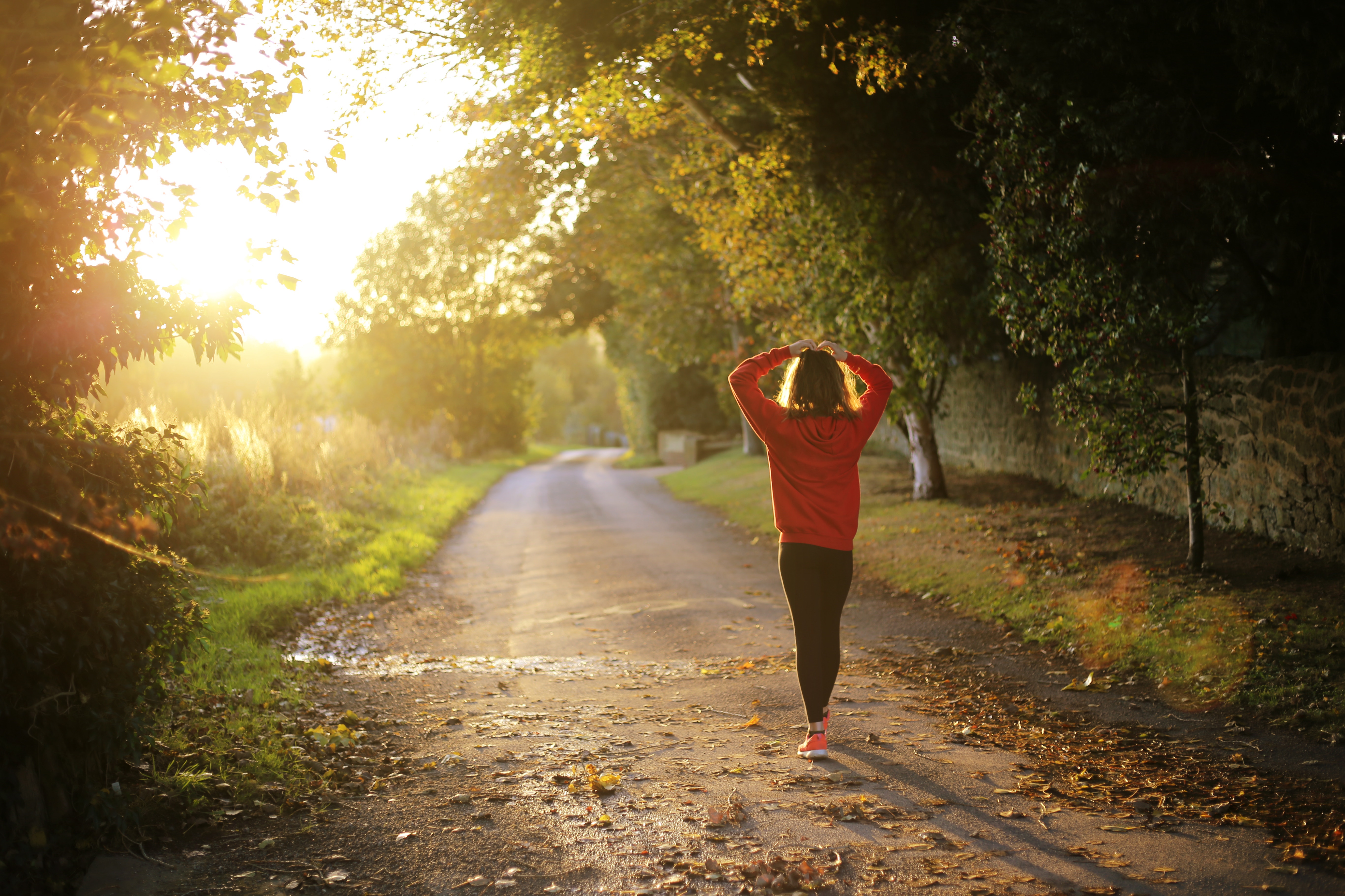 young person walking along road in sun